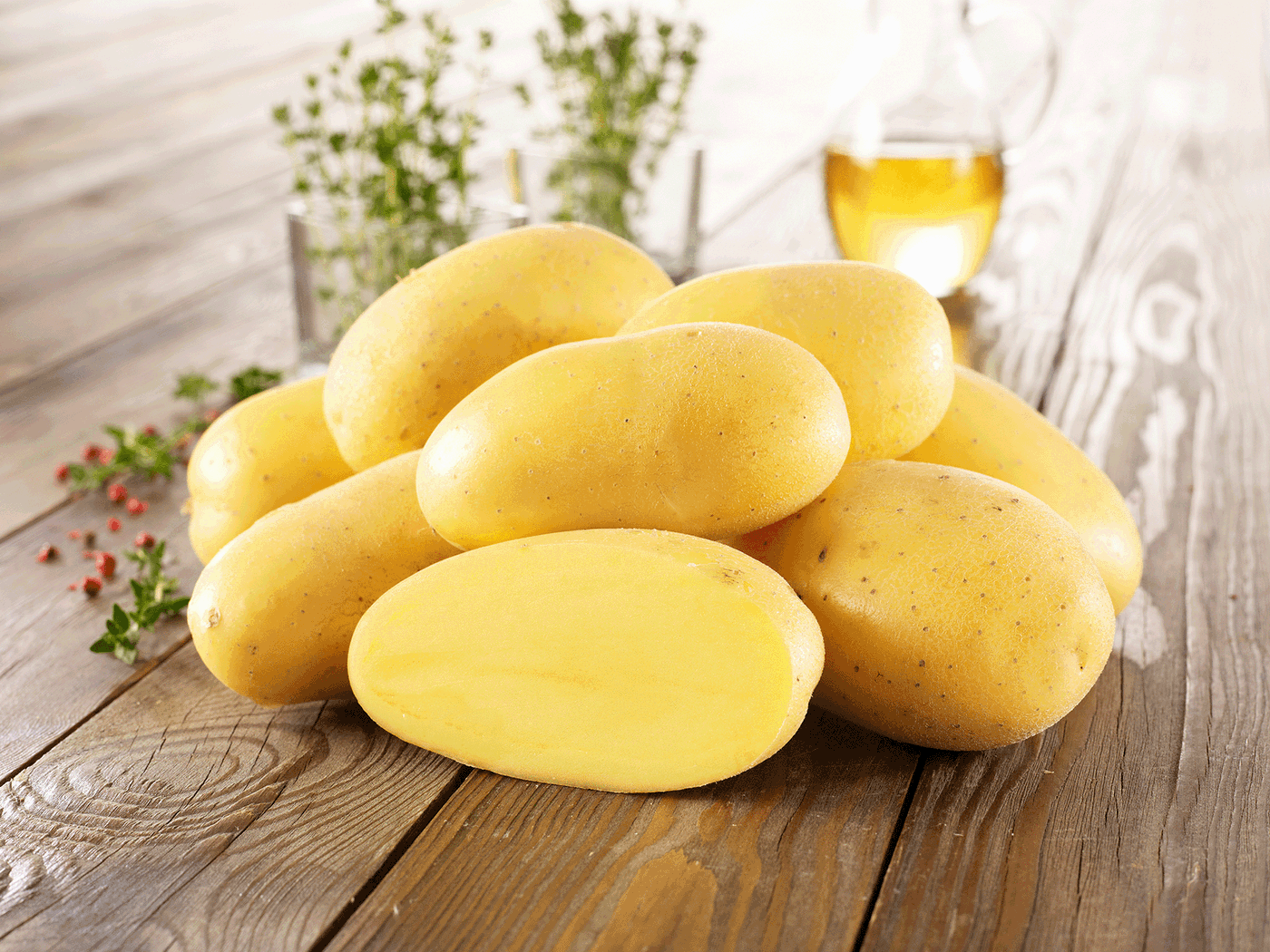 Gelbe Kartoffeln auf Holz, mit Ölflasche im Hintergrund.