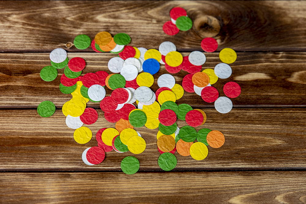 Bunte runde Konfetti liegen auf Holzoberfläche verteilt
