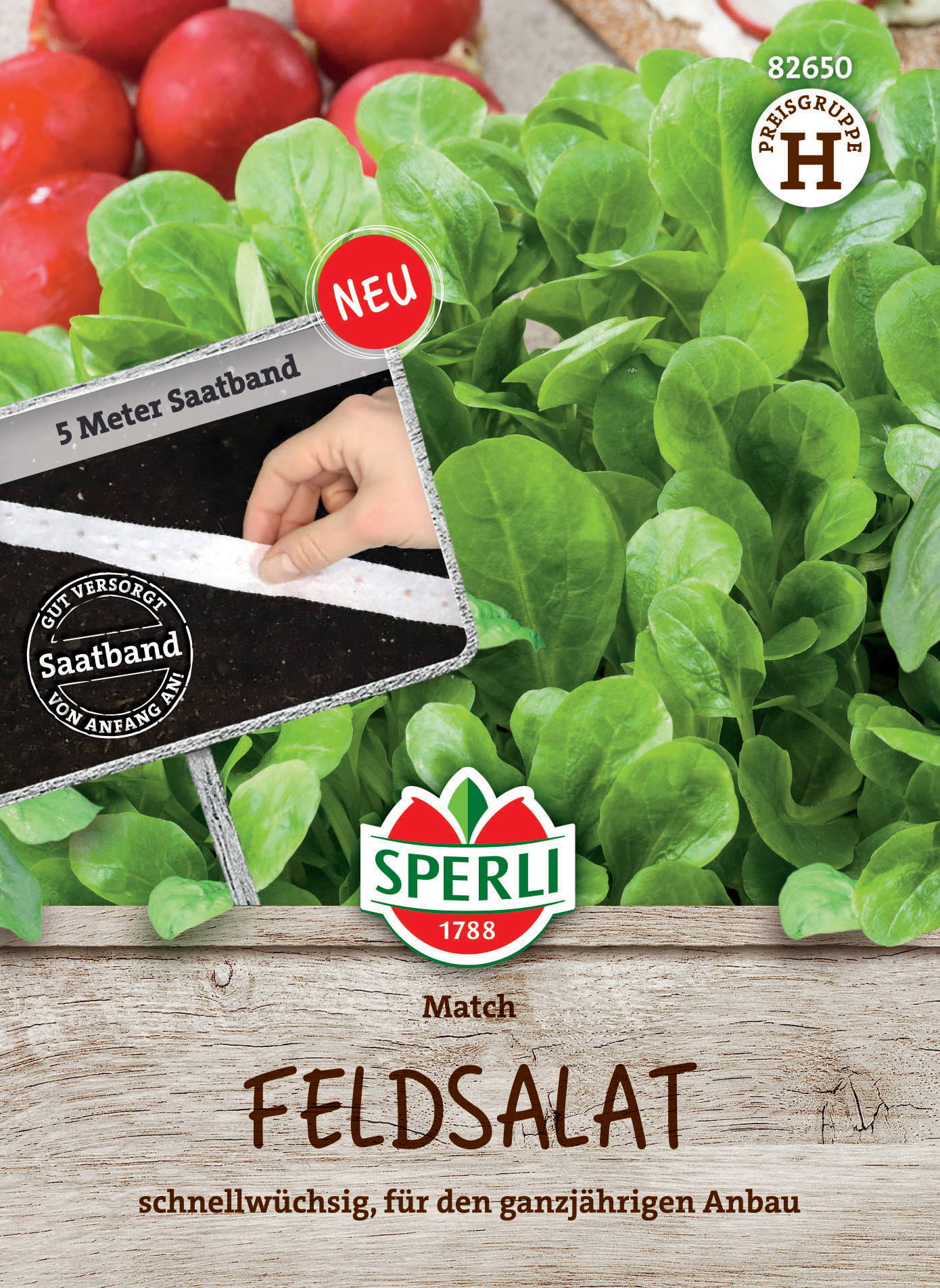 Grüner Feldsalat in einem Holzbehälter mit Schneidebrettern im Hintergrund, einer Hand, die eine Saatband-Tüte hält.