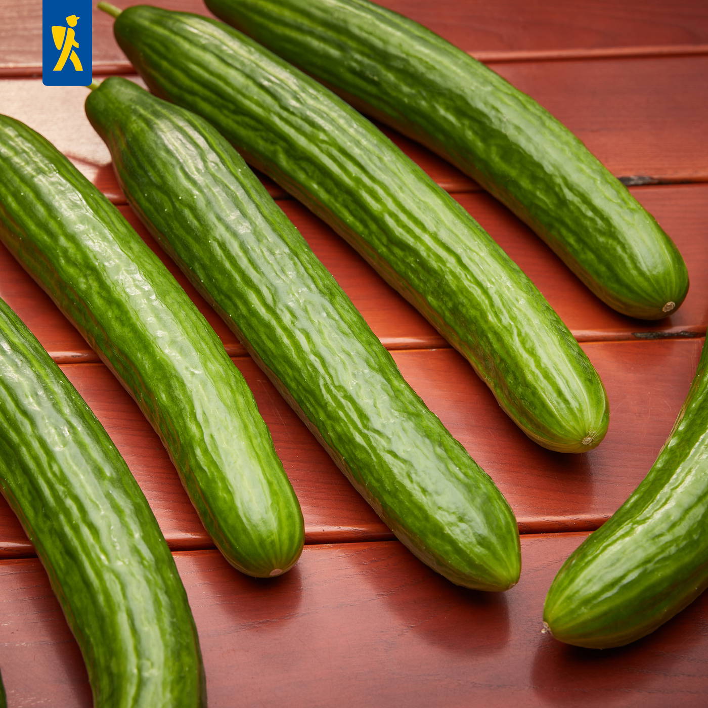 Mehrere Gurken liegen auf rotem Holzbrett.