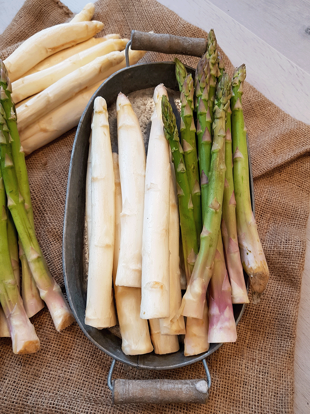 Weißer und grüner Spargel auf einem rustikalen_Boden.