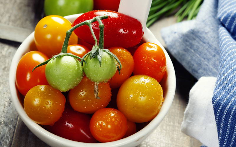 Mischung aus grünen, gelben, orange und roten Tomaten in einer Schale.