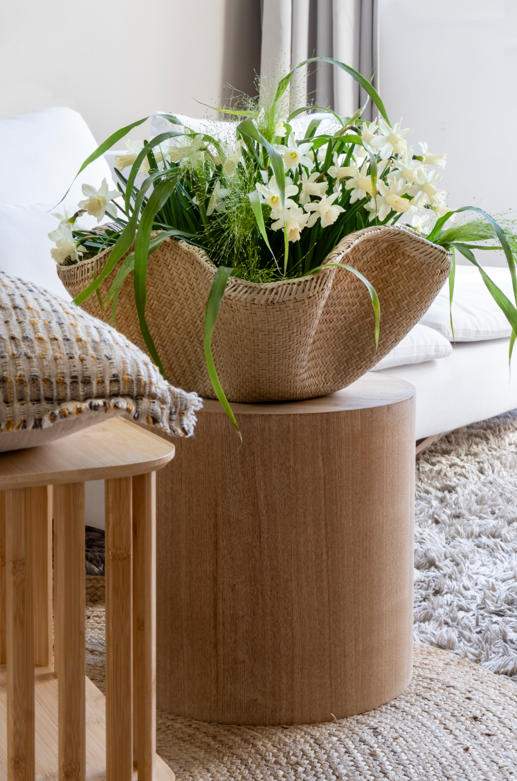 Blumen in einem großen Korb auf einem runden Holztablett im Wohnzimmer.