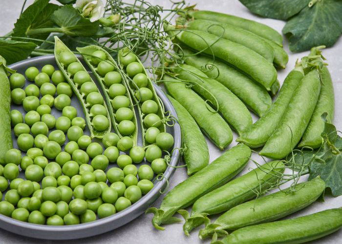 Grüne Erbsen in Schale, Peas and snow peas auf einer weißen Oberfläche.