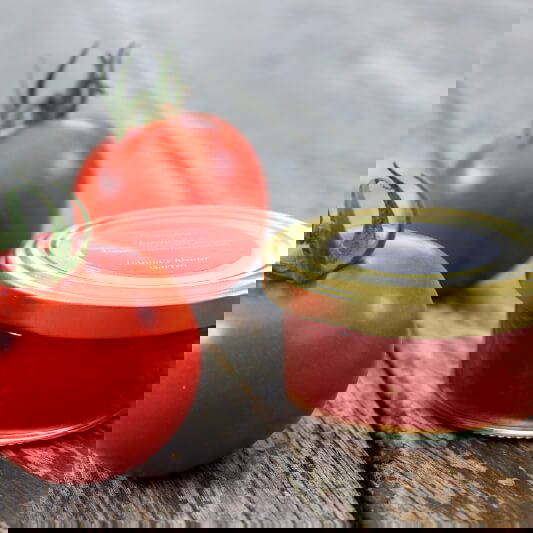 Zwei Tomaten und ein Glas Tomatenmark auf einer Holzoberfläche