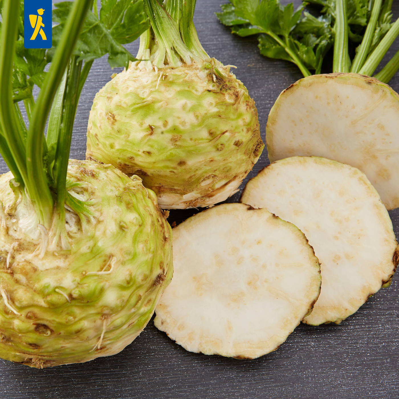 Zwei Kkwai-Kwai-Wurzeln, eine halbiert, auf schwarzem Holztablett mit grünen Blättern im Hintergrund.