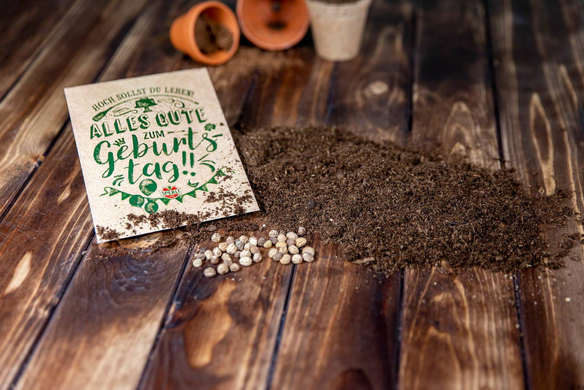 Geburtstagskarte mit Erde, weißen und schwarzem Pfeffer auf Holztisch.