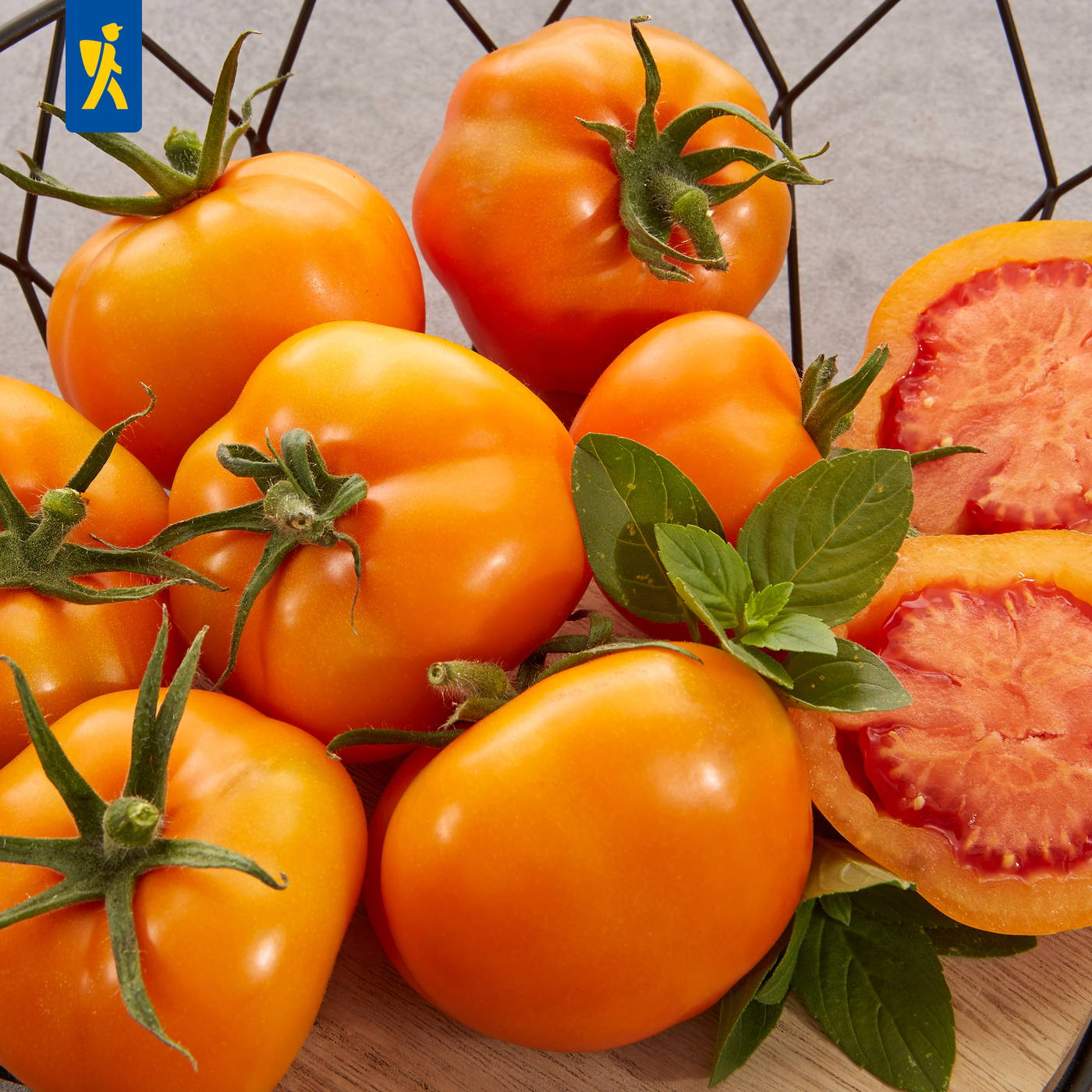 Mehrere geerntete Tomaten, einige geschnitten, mit grünen Blättern auf einem Holztisch.