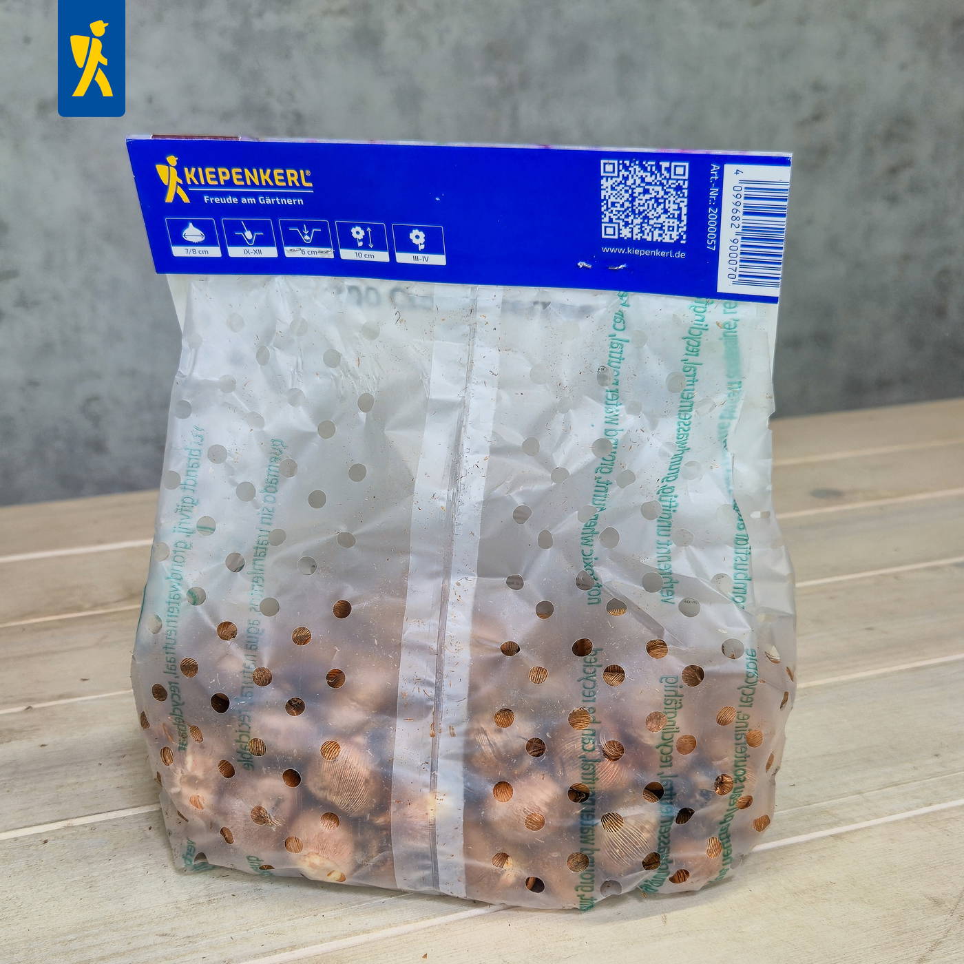 Durchsichtige Plastikverpackung mit perforierten Löchern und blauer Oberseite mit Beschriftung und QR-Code.