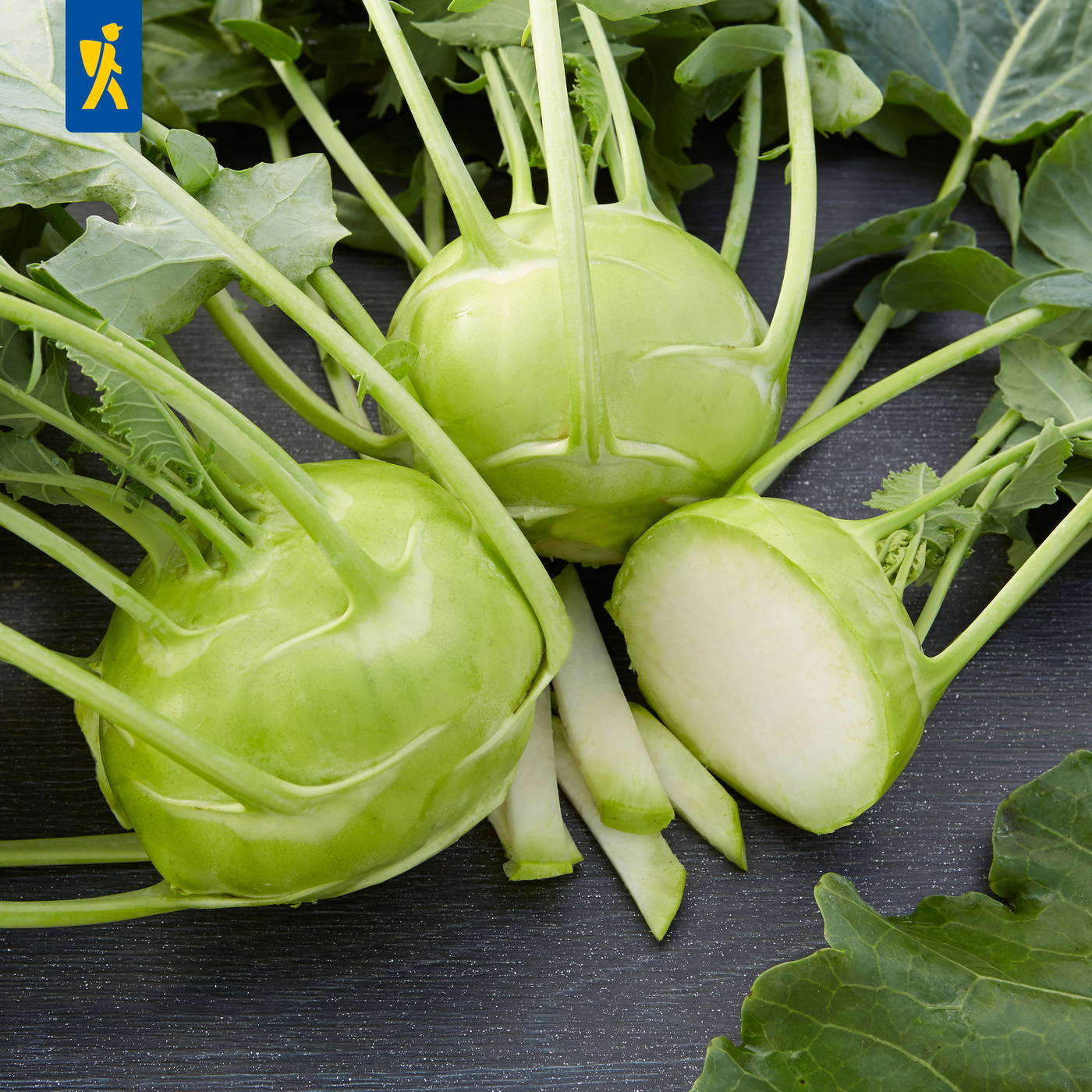 Grüne Kohlrüben mit grünen Blättern auf schwarzem Hintergrund, eine Hälfte angeschnitten.